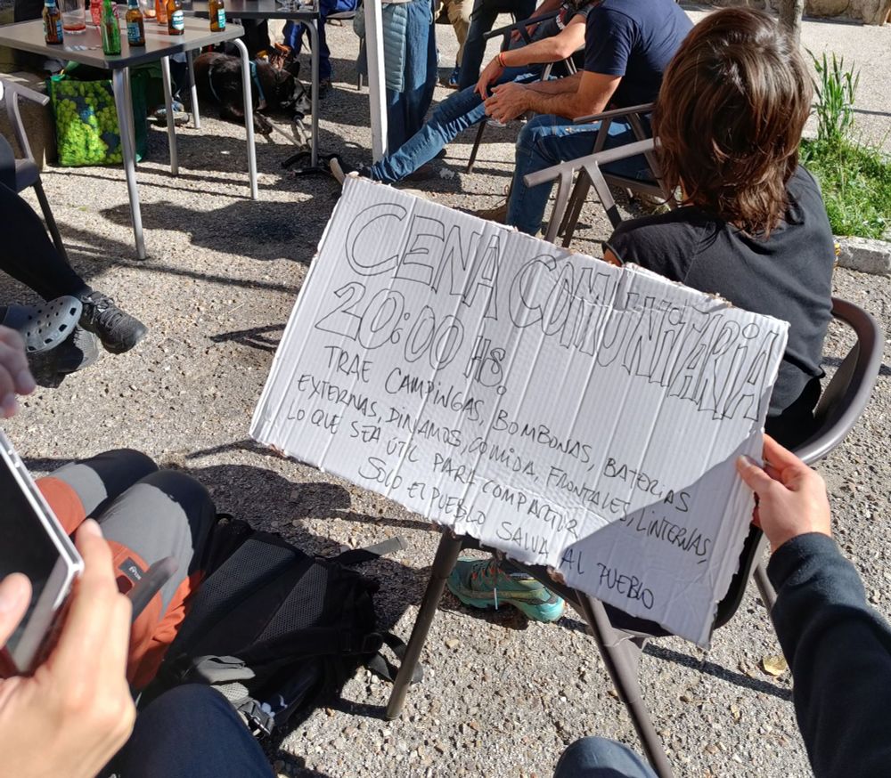 Cartel que anuncia una cena comunitaria para compartir gas y alimentos en el apagón 