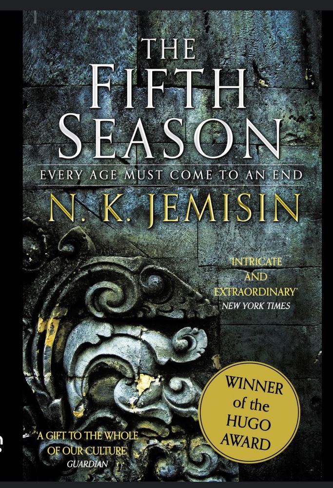 Cover of The Fifth Season by N. K. Jemisin. Gold badge announces that it is the Winner of the Hugo Award. Background image is of grey-blue stone, with an intricately-carved decoration in the bottom left corner. 