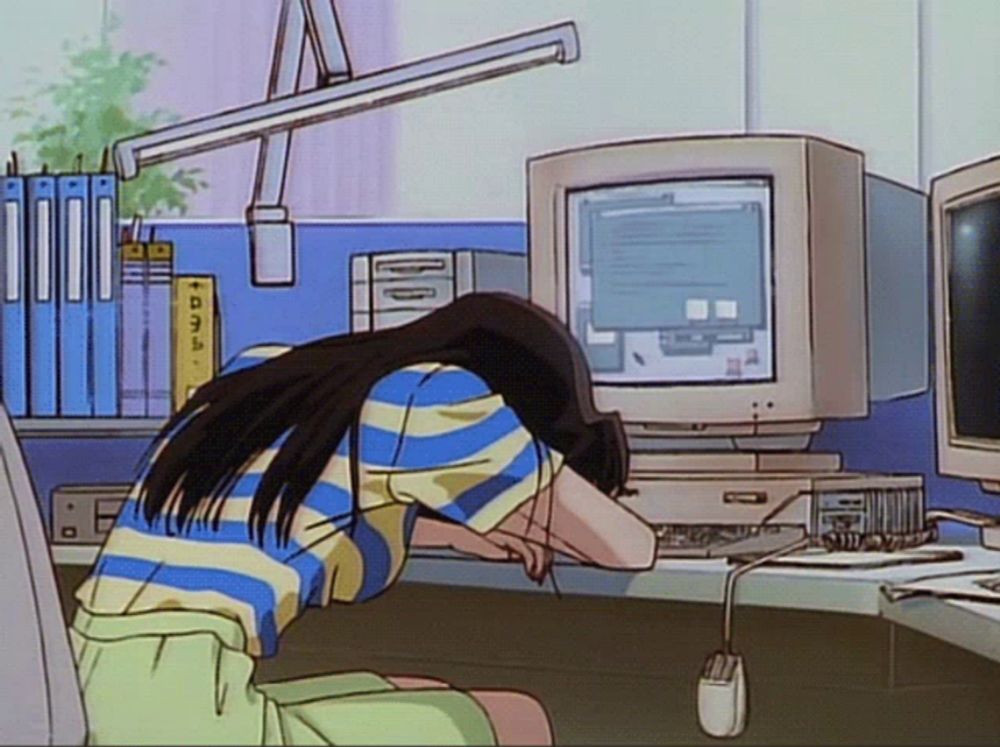 a girl is sitting at a desk with her head down in front of a computer monitor .