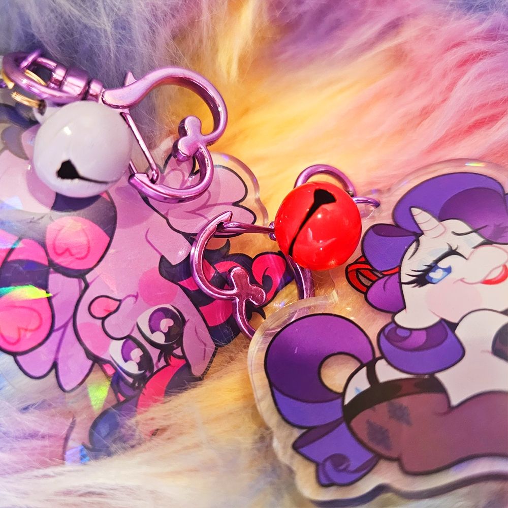 2 Acrylic Charms of Rarity and Twilight Sparkle wearing socks, both positioned to show off the colorful bells that come with the charms. 