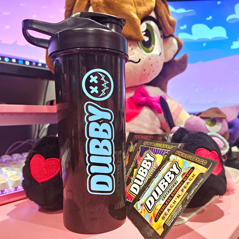 A picture of a 24oz Dubby themed energy drink cup, with 3 of their sample packs, posed with Befish's plushie in front of her computer monitors. Use code BEFISH to get 10% off your order. 