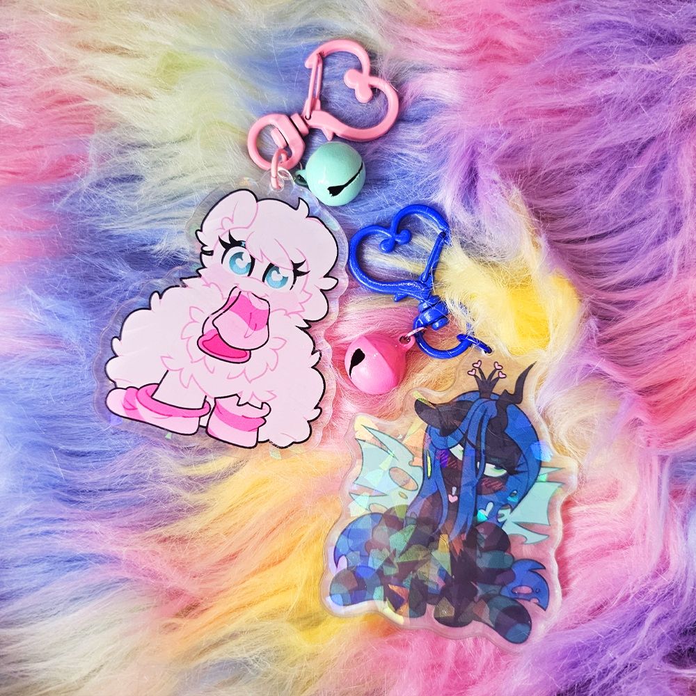 2 Acrylic Charms of Fluffle Puff and Chrysalis wearing socks, Chrysalis in black and green socks, Fluffle wearing dark pink socks and eating one of them. Both have matching bells. 