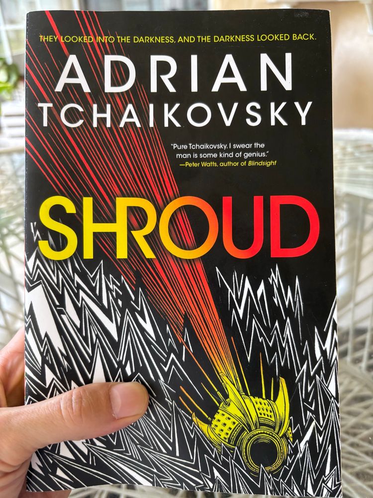 A yellow pod streaks into jagged darkness. The title, Shroud, hovers ominously above. The author’s name—Adrian Tchaikovsky—appears in bold at the top. 