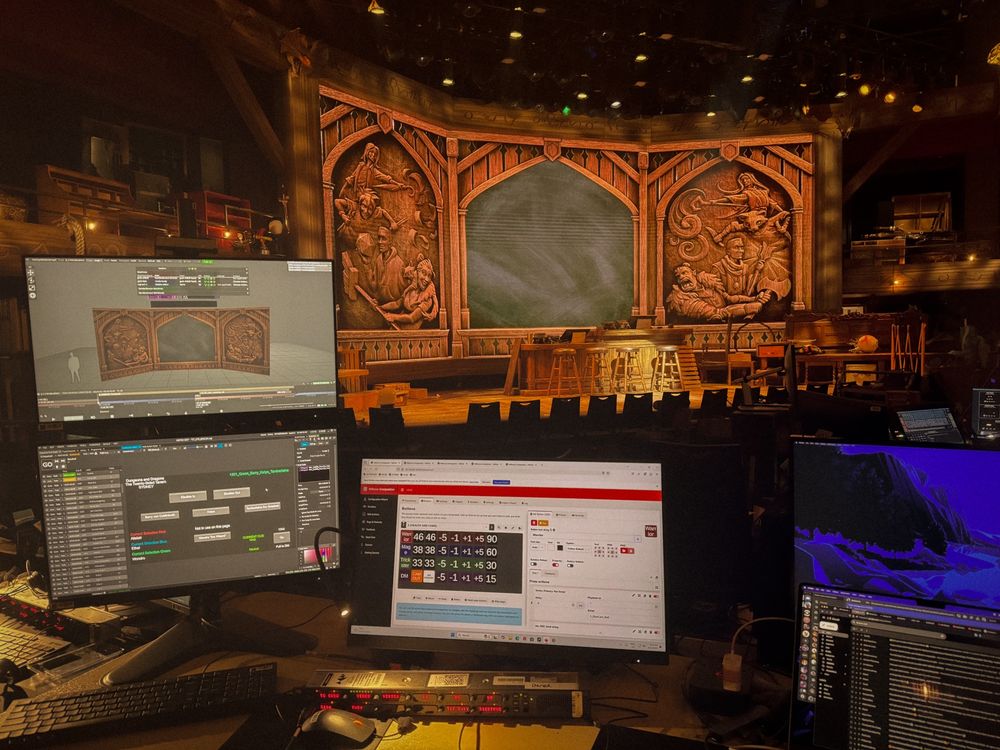 Behind the video tech table for the Twenty-Sided Tavern, showing various monitors that control the video elements of the show, in front of the stage itself.