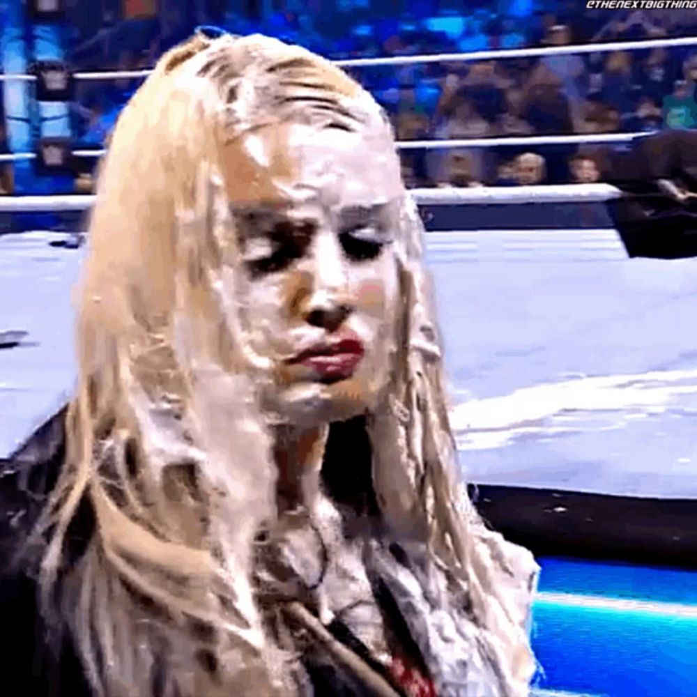 a woman with white paint on her face is in a wrestling ring .