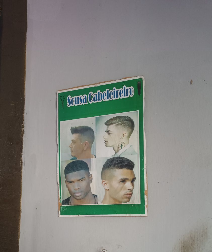 Placa de um salão de cabeleireiro com 4 tipos de corte escrito "Sousa Cabeleireiro" 