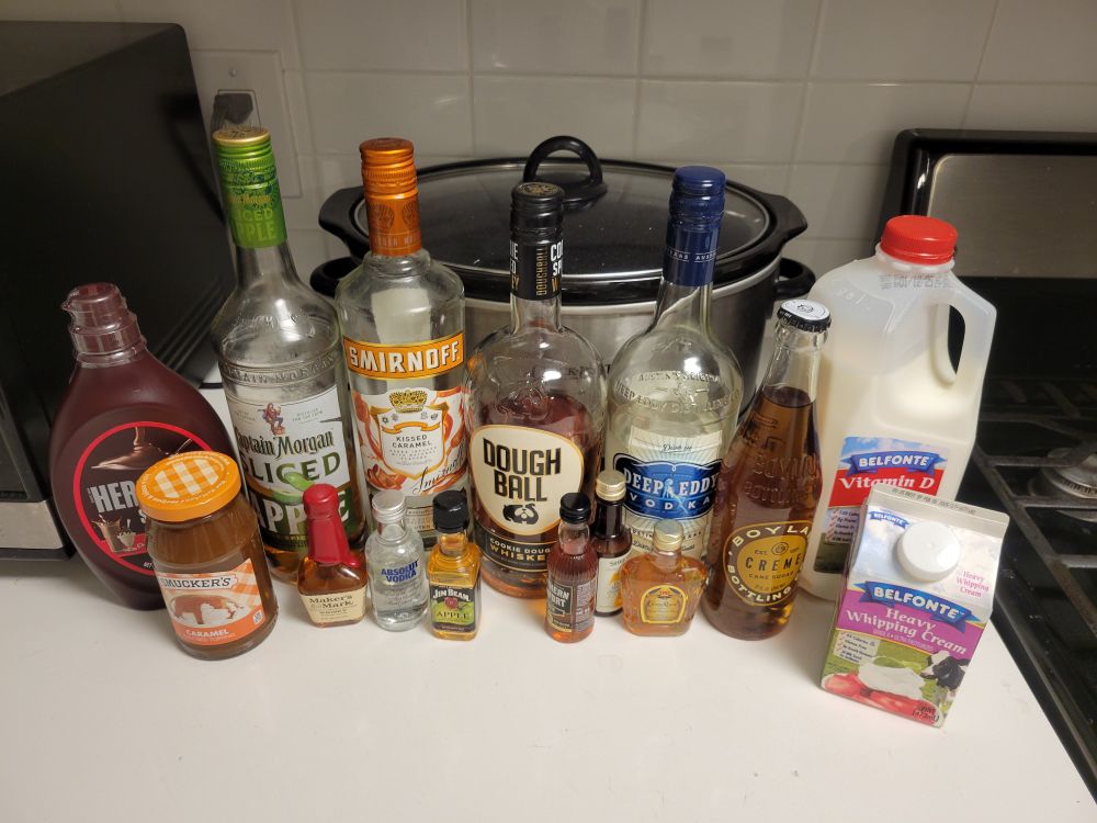 A wide shot of various loquids being mixed into alcohol for New Years Eve. From left to right, back row:
1. Hershey's chocolate syrup
2. Captain Morgan Sliced Apple rum
3. Smirnov Kissed Caramel vodka
4. Dough Ball Cookie Dough whiskey
5. Deep Eddy vodka
6. Boylan Bottling Co Vanilla Creme soda
From left to right, front row:
1. Smuckers Caramel topping
2. Maker's Mark whiskey shot
3. Absolute Vodka shot
4. Jim Bean Apple shot
5. Southern Comfort Black whiskey shot
6. Seagrams Dark Honey whiskey shot
7. Crown Royal whiskey shot.

I will not be drinking all of this tonight.  That would be stupid.  And dumb.  