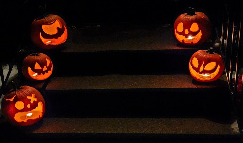 Five lit jack-o'-lanterns, sitting nicely on steps.