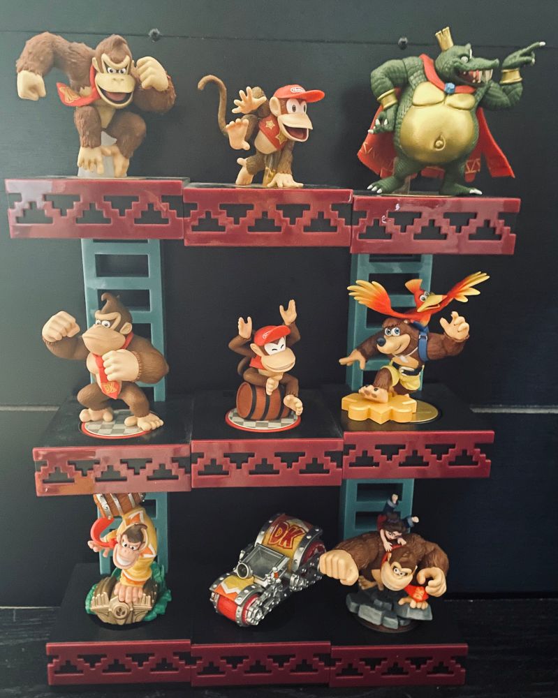 Donkey Kong Universe amiibo on a Donkey Kong 25m girder construction site display stand. Left to right, top to bottom: Donkey Kong (Super Smash Bros. Ultimate), Diddy Kong (Super Smash Bros. Ultimate), King K. Rool (Super Smash Bros. Ultimate), Donkey Kong (Super Mario), Diddy Kong (Super Mario), Banjo & Kazooie (Super Smash Bros. Ultimate), Turbo Charge Donkey Kong (Skylanders), the Barrel Blaster vehicle (Skylanders), and Donkey Kong & Pauline (Donkey Kong Bananza).