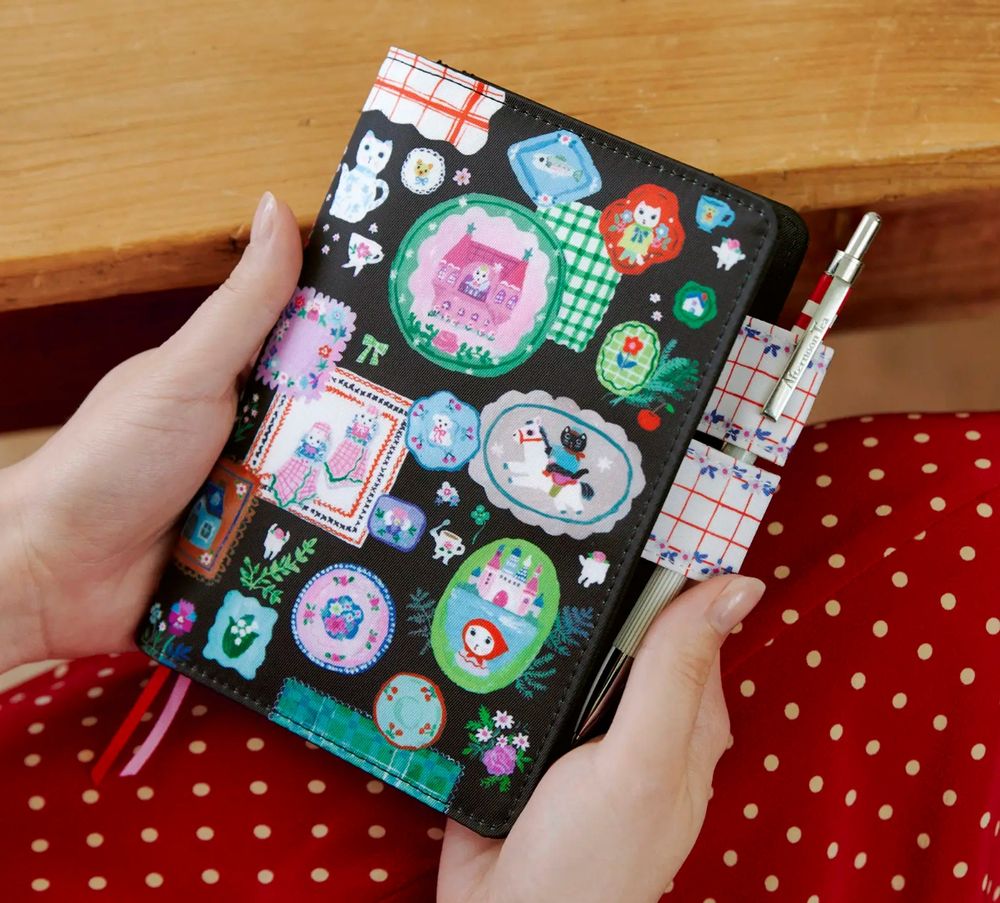 The "White Cat's Table Decorations" journal from artist Yumi Kitagishi -- the theme for this techo cover is “table decorations,” with sticker-like illustrations of little items that would make it onto a table for a tea party. There's a white cat vase like one that's very cute.