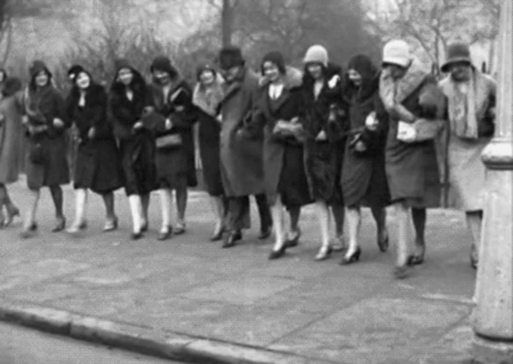 a group of women are walking down a sidewalk .