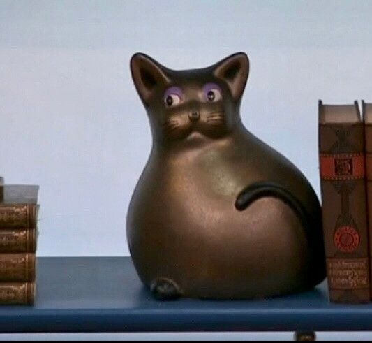 A shot of the Big Brother bronze and bulbous cat figurine giving side eye called Louise without the red ribbon and key around her neck