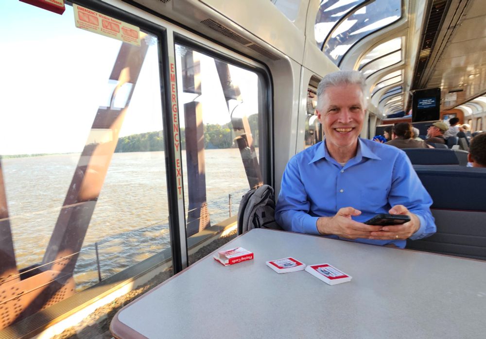 Middle aged man playing cards in the observation car of a train while crossing the Mississippi.