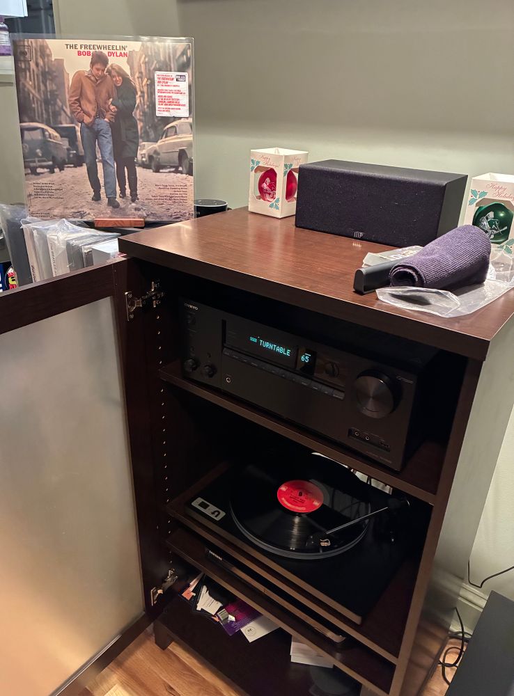 https://www.discogs.com/release/35770609-Bob-Dylan-The-Freewheelin-Bob-Dylan

Record playing on a U-Turn Orbit Plus turntable w/Ortofon 2M Blue cartridge. The album jacket is displayed on the entertainment center.