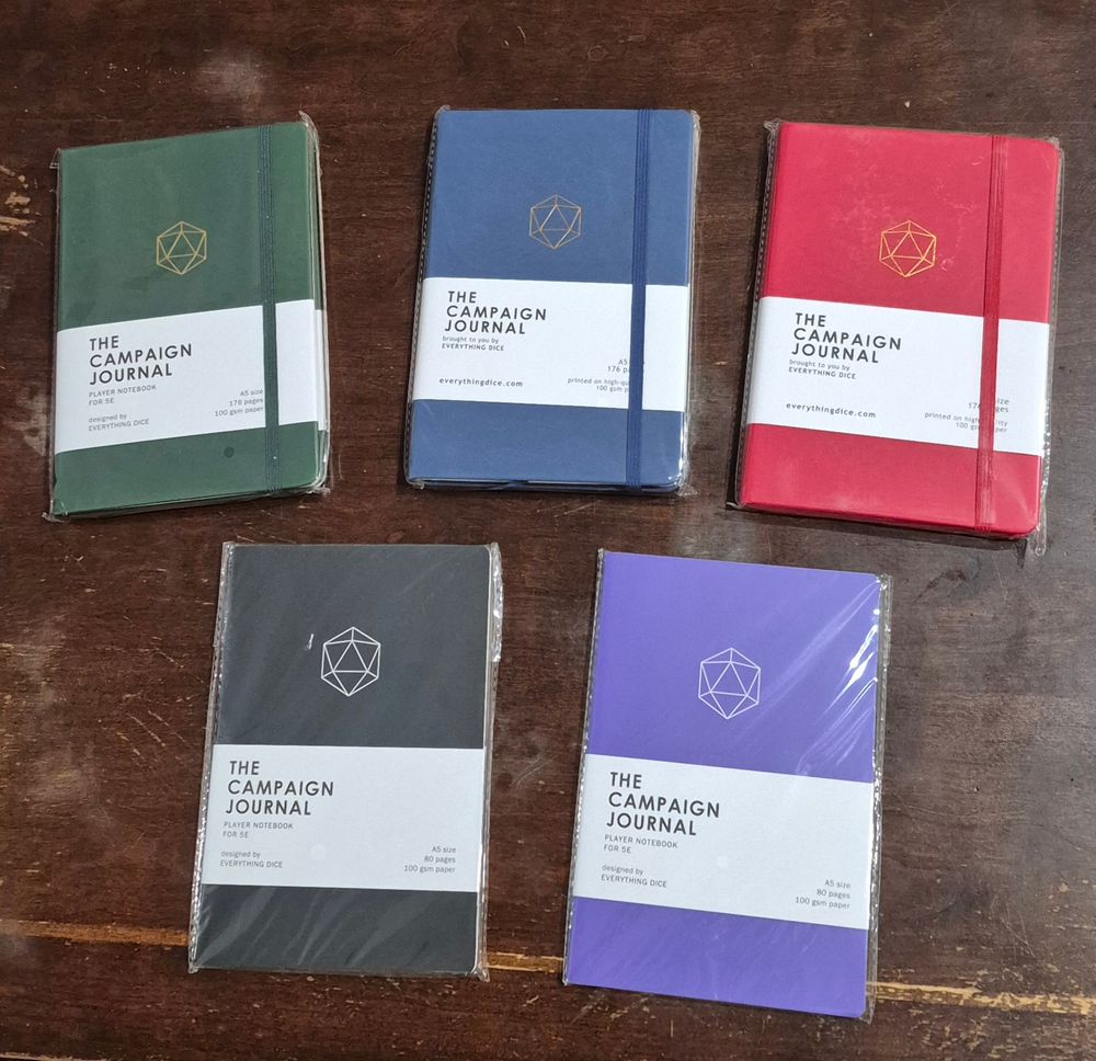 Campaign journals from Everything Dice! The top 3 are red, blue, and green hardcovers, while the bottom two are black and purple soft covers.