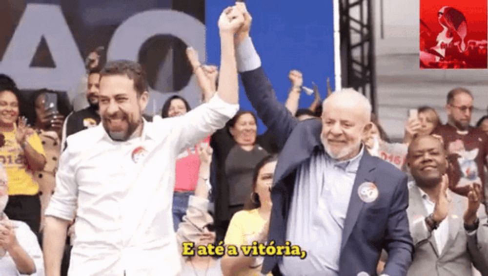 a man in a suit holds up another man 's fist and says " eate a vitoria " in yellow