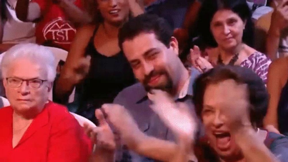 a group of people are sitting in a stadium applauding a man .