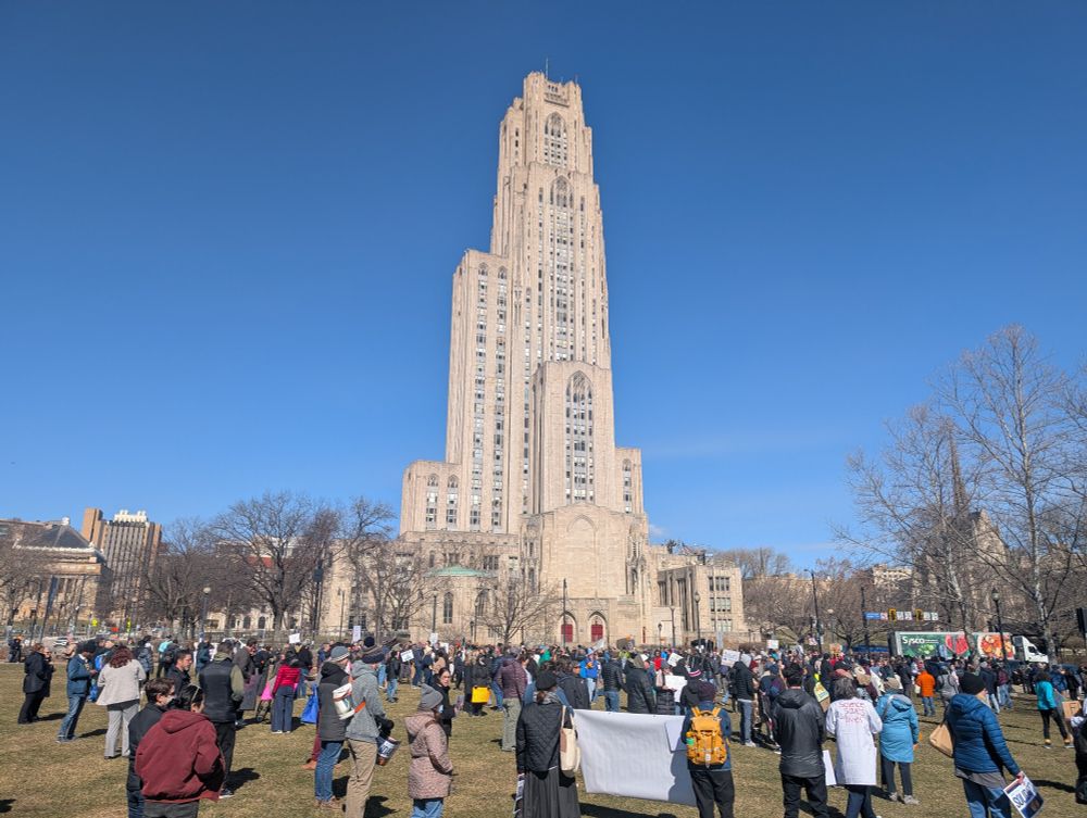 Cathedral of Learning with crowd gathered on Schenley Plaza grass in foreground 