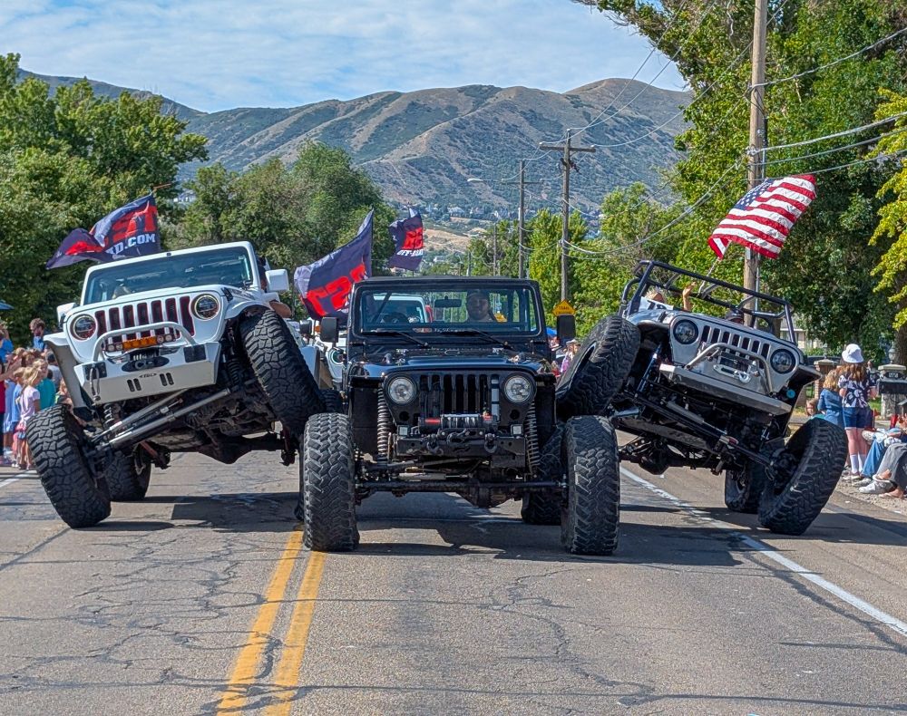 Three jeeps doing a stunt where the ride over each other's tires