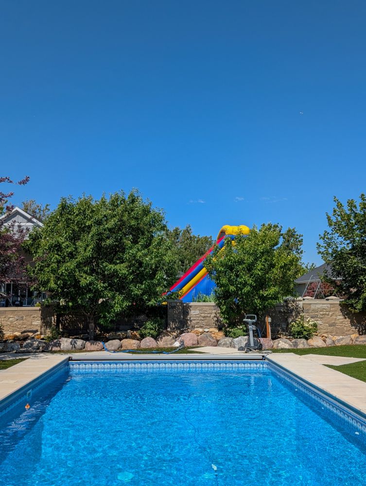 A backyard pool. The neighbors have a gigantic bouncy house.