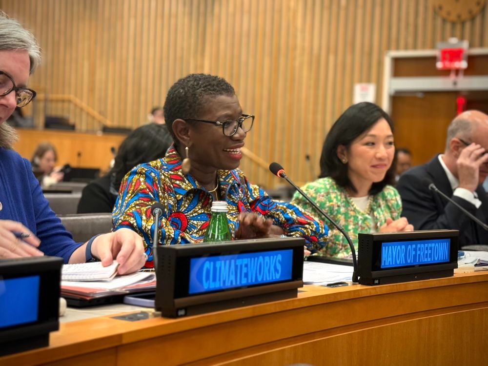 A photo of Mayor Yvonne Aki-Sawyerr at the United Nations in New York. She is speaking into a microphone and smiling.