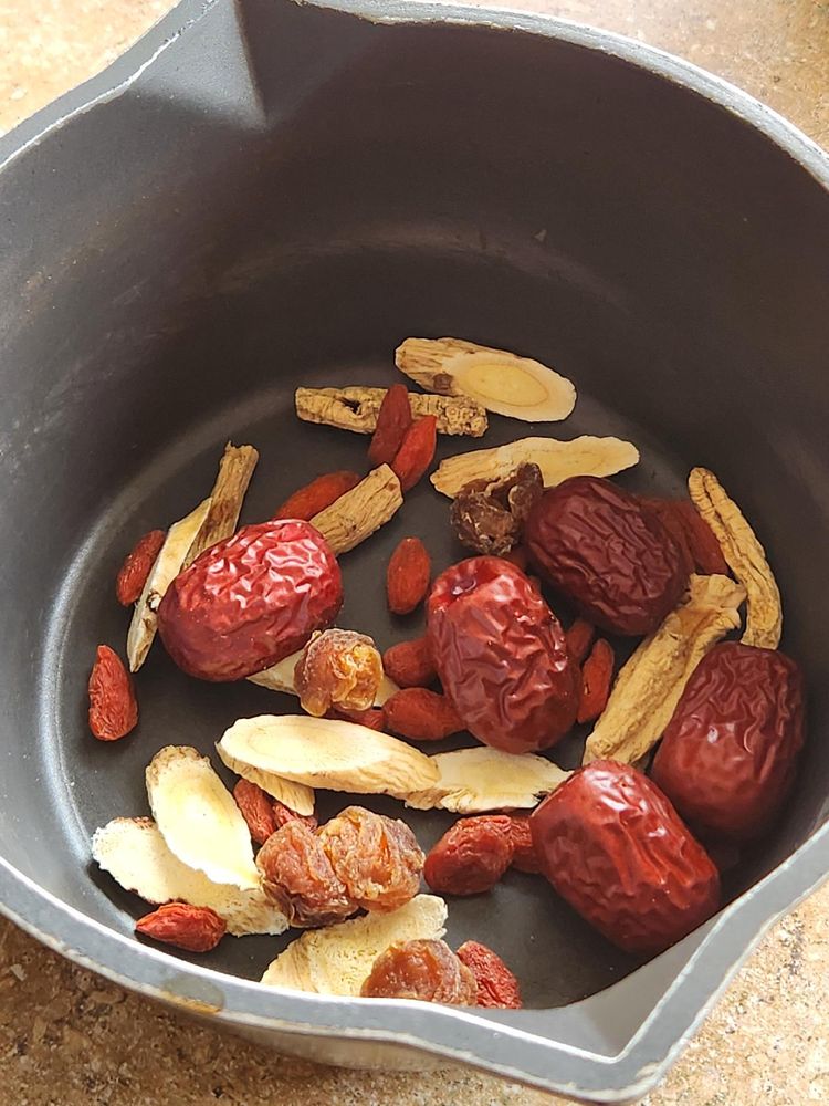 a small saucepan containing what appears to be (from visual inspection): hong zao, gou qi zi, dang shen, bai zhi, and something else I couldn't identify in my exam last week