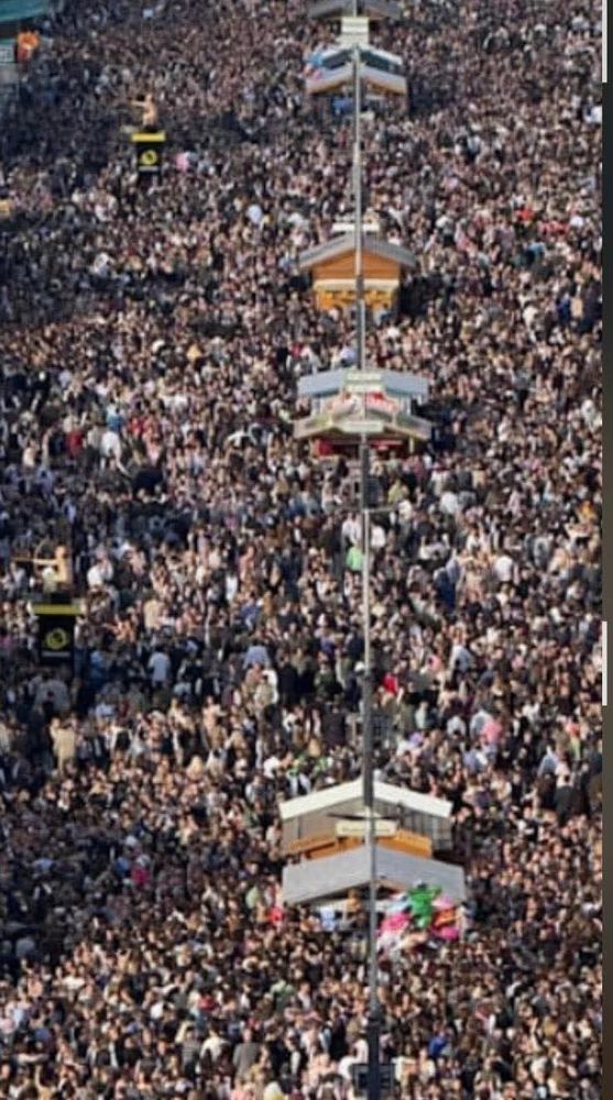 This is an image that looks TO ME like an enormous pile of garbage - like a tip/dump - and there are small square stacks of something thrown upon the top of it that are connected by a thin pole of something. In fact it is a picture of Octoberfest, so crowded with a mass of humanity that it boggled my mind. The “square things” are a smattering of stalls (selling like pretzels and beer I’d guess?) I don’t know why they look connected unless it’s some kind of overhead structural support or electricity or something. I feel like I’m being smothered just by looking at such a crowd.  