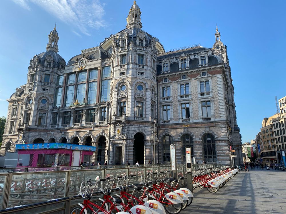 The historic train station in Antwerp. Blue skies in the background and a row of rental bikes in the foreground