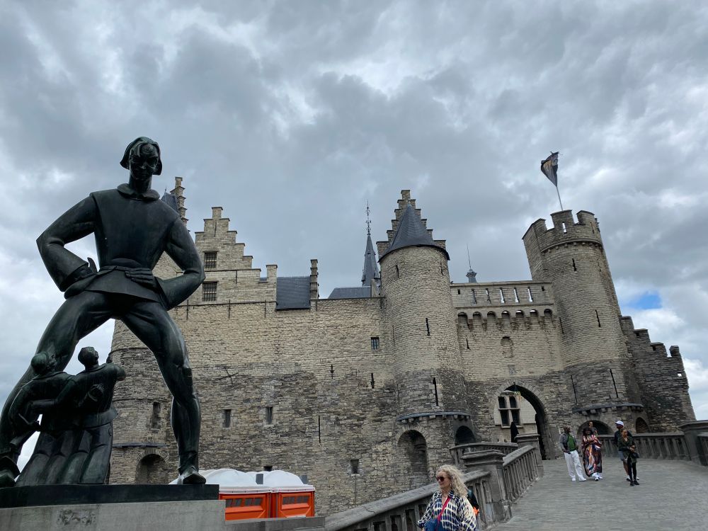 The oldest building in Antwerp! Very dramatic medieval towers with a menacing statue of a giant in the foreground 