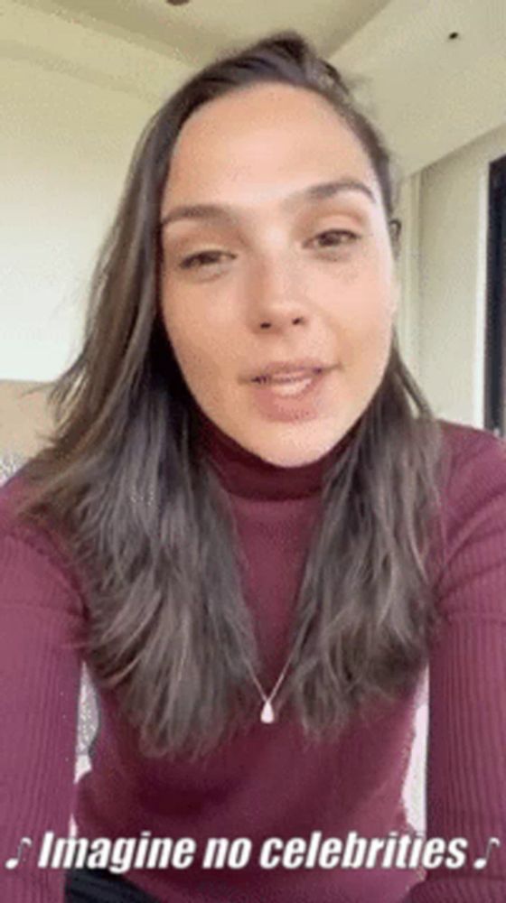 a woman wearing a turtleneck sweater and a necklace is talking to the camera .