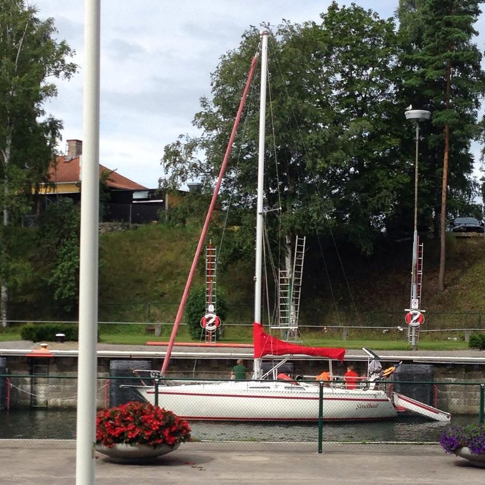 A view from #södertäljekanal from the time before the renovation. A sailboat with a beautiful red sail that matches the red geraniums on the quay