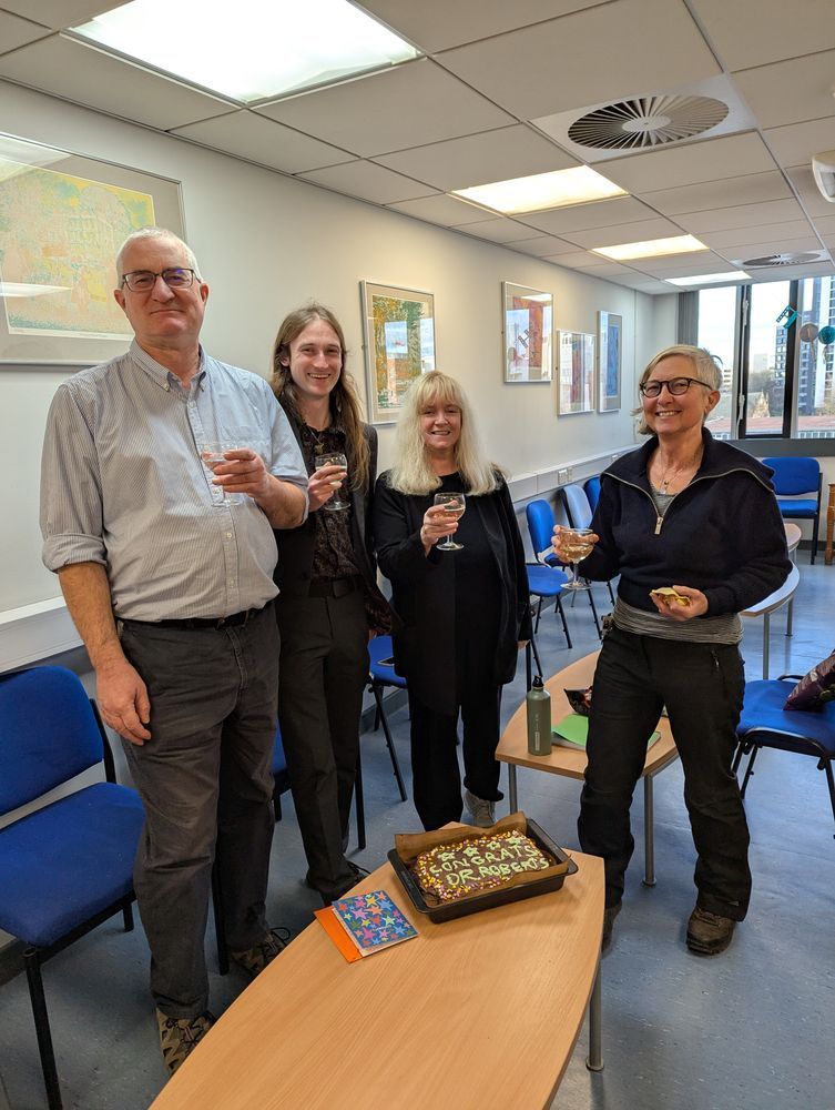 A photograph of Jonathan Roberts (second from left) with his supervisors, enjoying a glass of fizz and a cake.