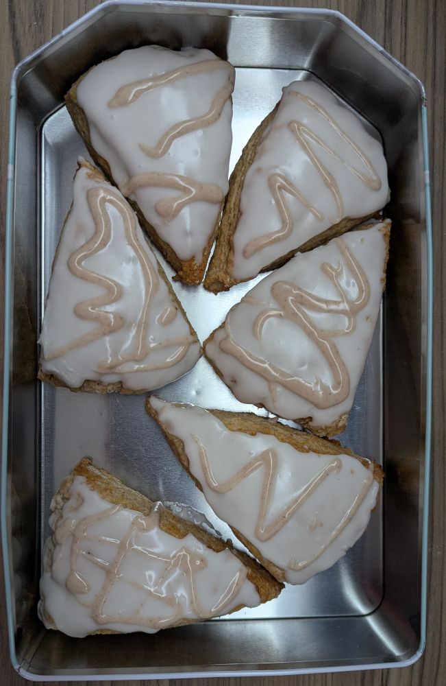 A tin full of six triangle scones covered in icing