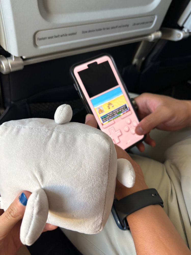 small shark plushie watching human playing pokemon mystery dungeon explorers of sky on the airplane :)