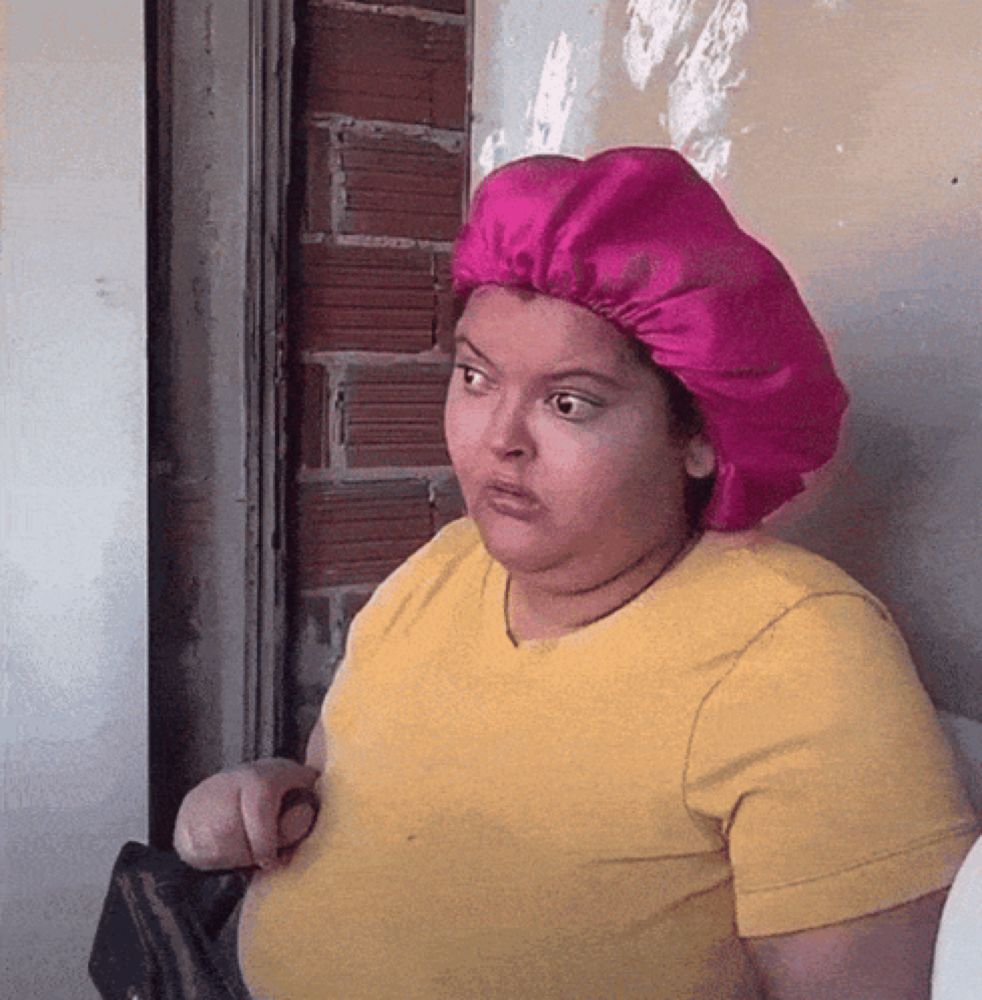 a woman wearing a yellow shirt and a pink hat looks confused