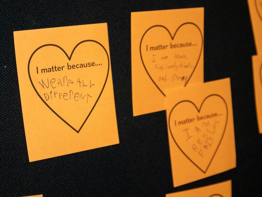 Orange heart-shaped notes on a board, written by children. Messages include: “I matter because we are all different” 