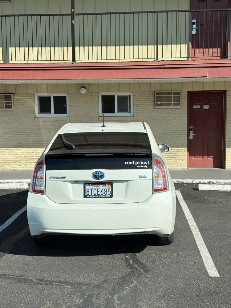 white prius with a sticker that says 'cool prius! —nobody'