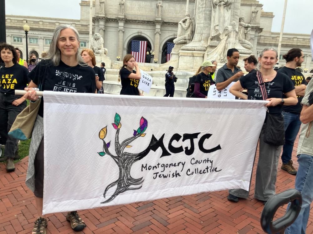 MCJC at the Stop Starving Gaza action, holding a banner with our logo.