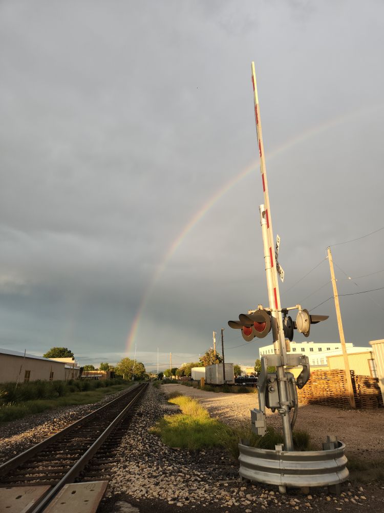 Double rainbow over railroad tracks at golden hour