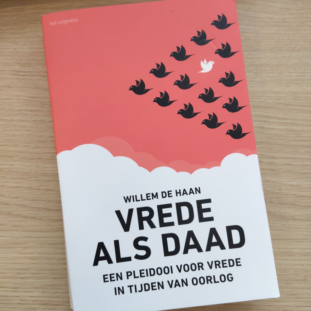 Boek over: "Vrede als Daad: Een Pleidooi voor Vrede in Tijden van Oorlog" (bot uitgevers). De cover toont een rode hemel met witte wolken en een groep zwarte vogels die in formatie vliegen. Één witte vogel (/vredesduif) vliegt echter in tegengestelde richting tegen de zwerm in.