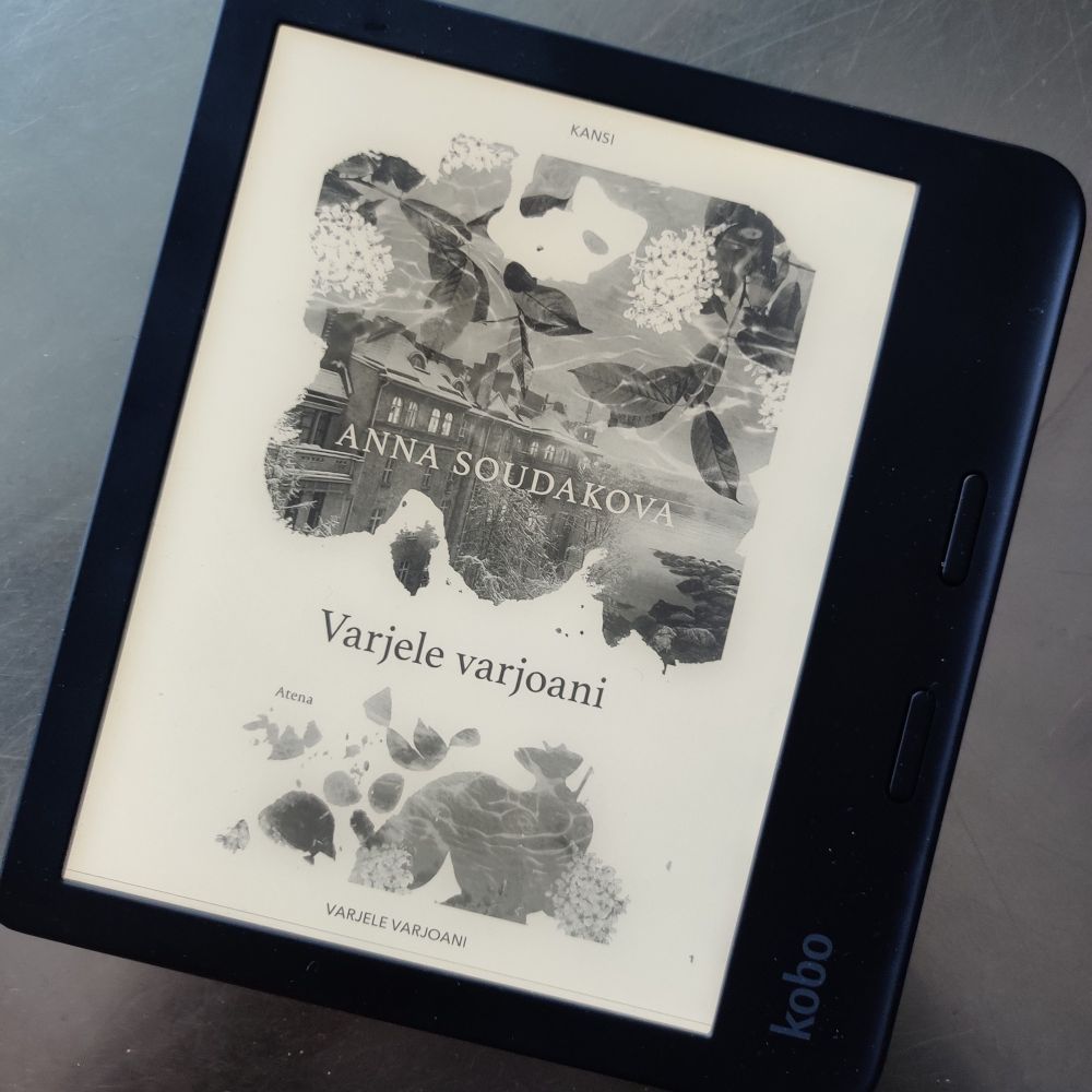 Musta Kobo-merkkinen lukulaite metallipöydällä. Lukulaitteessa näkyy kansikuva Anna Soudakovan kirjasta Varjele varjoani.