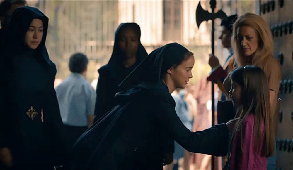 a woman in a nun 's robe talks to a little girl