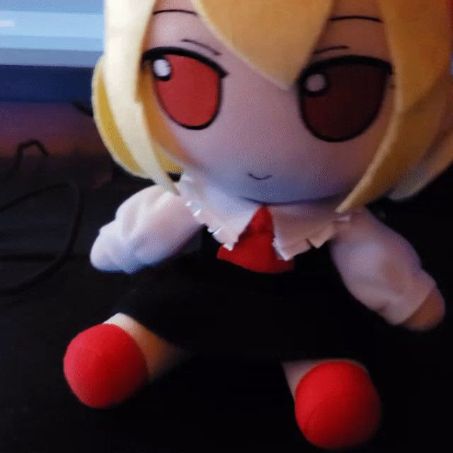 a stuffed doll with blonde hair and red eyes sits on a table