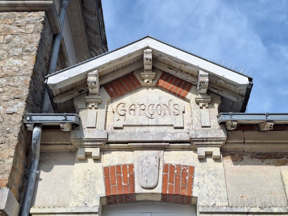 Fronton d'une ancienne école oû est gravé le mot Garçons. Façade blanche et briques. Pornichet.