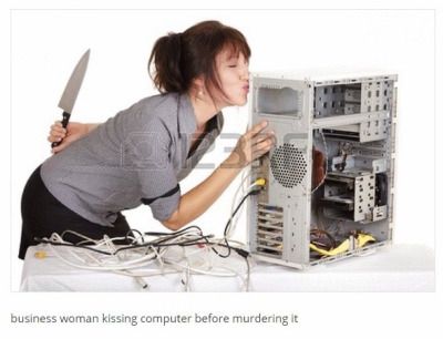 A stock photo of a woman standing next to an old partially disassembled PC and kissing it, holding a knife behind her back. A caption below reads “business woman kissing computer before murdering it”
