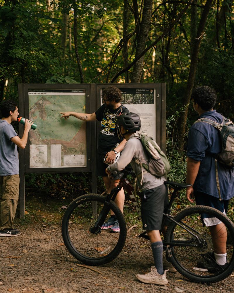 A group of people look at a map to decide the beat route for a mountain biking day trip.