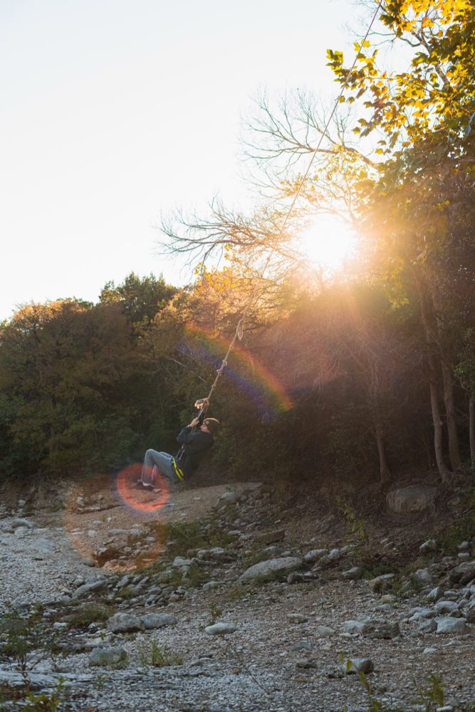 A man swings on a rope swing over a dried creek bed in Austin, Texas. 