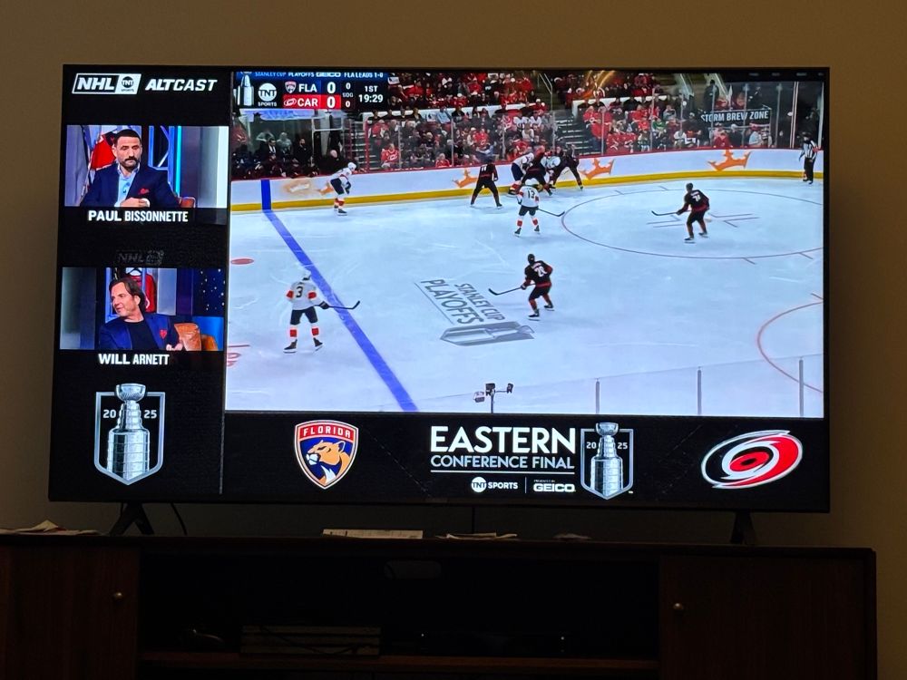 TV playing Carolina Hurricanes vs Florida Panthers hockey game. On the side of the screen are two commentators. One of them is Will Arnett with his name displayed. 