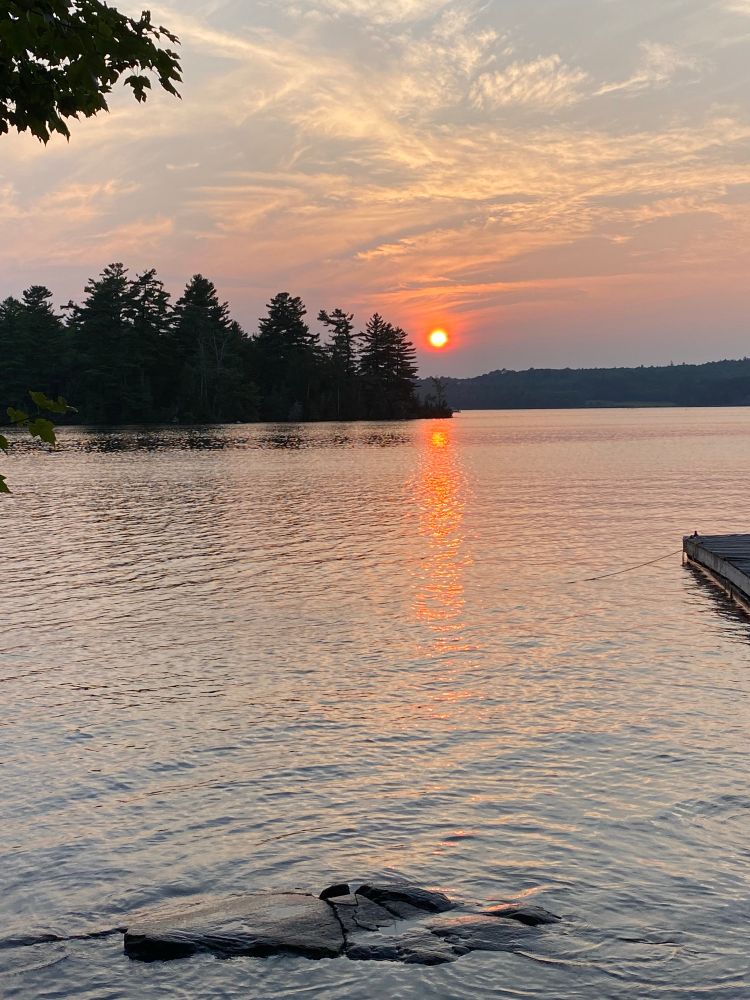 Sunset with an island in the distance and a rock under water in the foreground 