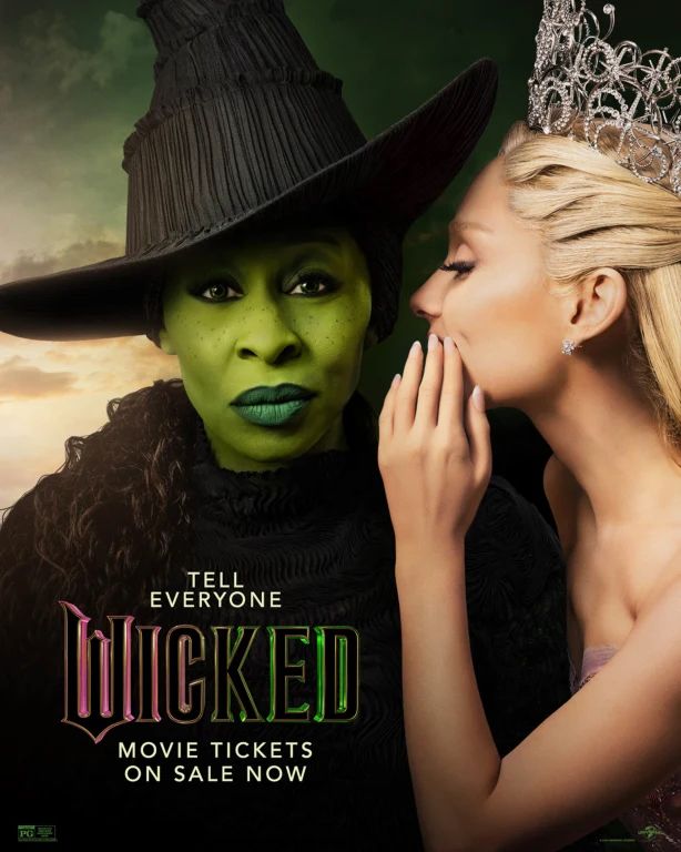 The promo poster for the movie Wicked. Ariana Grande as Glinda is whispering into the ear of Cynthia Erivo as Elphaba. Written in the lower right corner: TELL EVERYONE. WICKED MOVIE TICKETS ON SALE NOW.